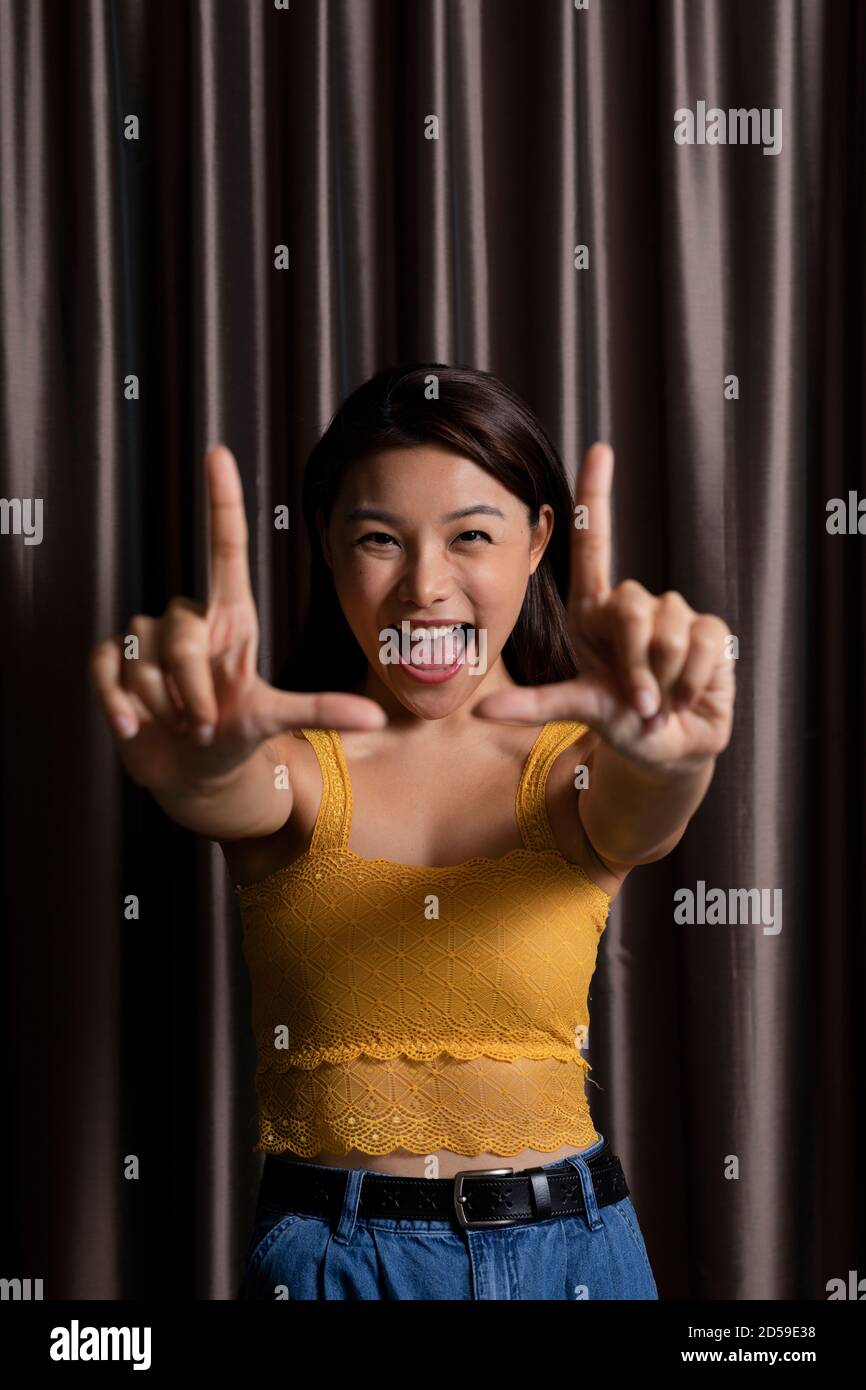 Porträt einer Frau vor einem Vorhang machen Ein Fingerrahmen Stockfoto
