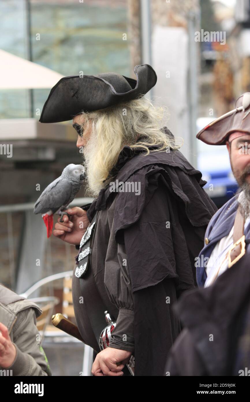 Bärtiger Mann, gekleidet als Pirat mit Tricorne-Hut, lebendem Papagei, Schwert und Pistole Stockfoto