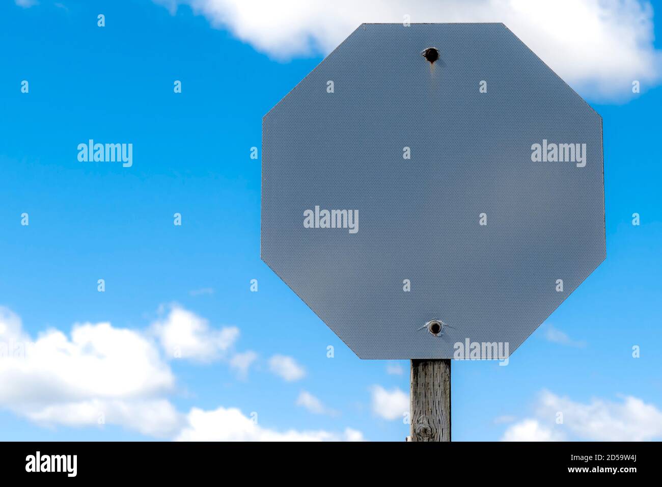 Ein leeres Stoppschild. Die Färbung hat sich vollständig abgenutzt, so dass nur das leere Metallschild. Auf der Oberfläche befindet sich ein feines Hexadezimalmuster. Blauer Himmel mit einigen c Stockfoto