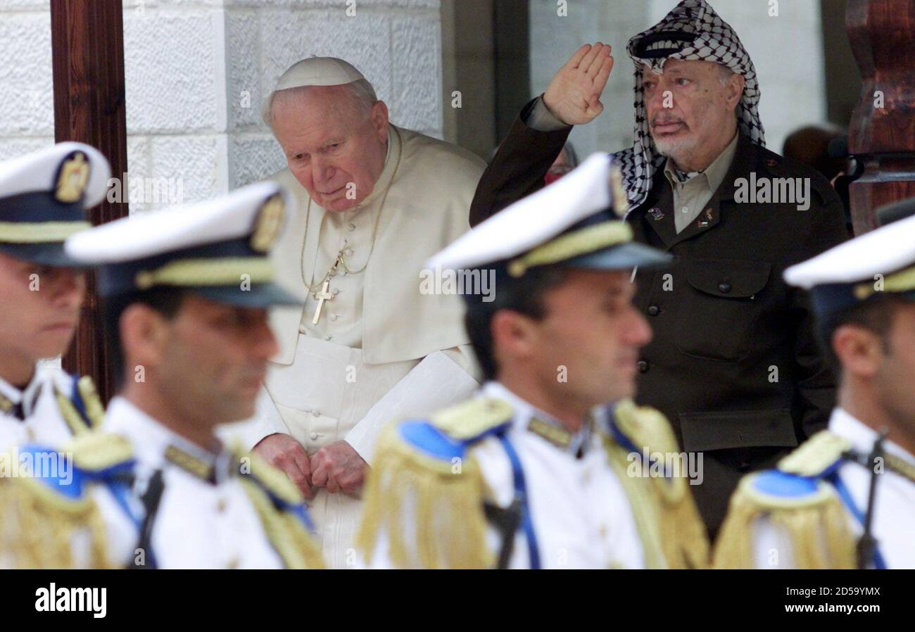 Der palästinensische Präsident Yasser Arafat begrüßt seine vorbeiziehende militärische Ehrenwache, während er neben Papst Johannes Paul II. Bei der offiziellen Begrüßungszeremonie des Papstes im Arafat-Hauptquartier in Bethlehem am 22. März stand. Der Papst fuhr fort, auf dem Krippenplatz eine Masse Meter vom Geburtsort Jesu in der Geburtskirche zu liefern. Stockfoto