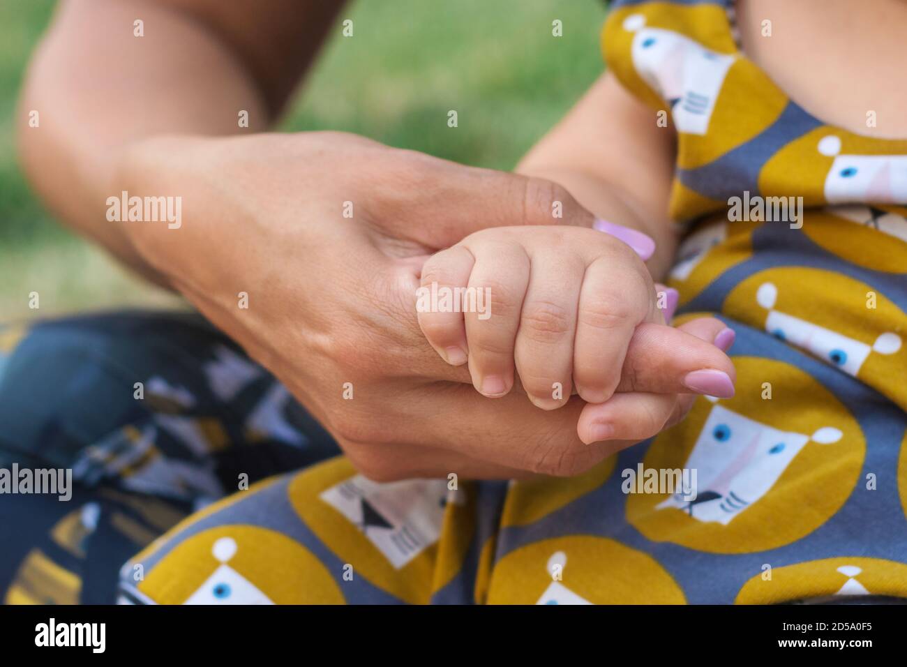 Eine Babyhand hält die Hand der Mutter. Glückliches Familien- und Babyschutzkonzept Stockfoto