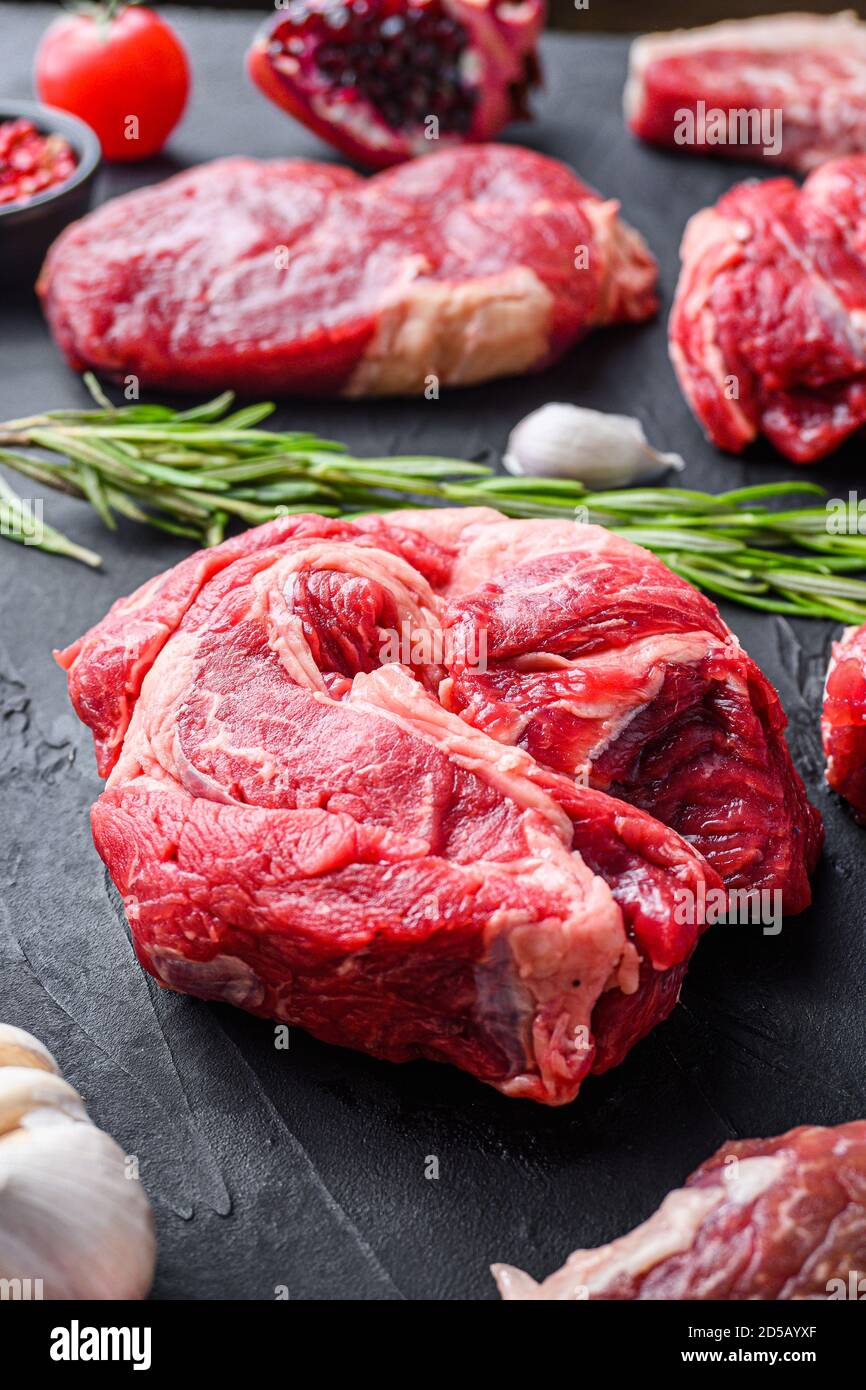 Chuck Roll Beef Steak Cuts, mit Kräutern, Würze auf schwarzem Tisch, Seitenansicht. Stockfoto