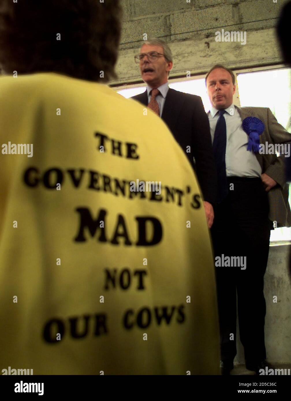 Premierminister John Major spricht die Bauern an, als eine Frau in einem Hemd mit dem Slogan "die Regierung ist verrückt, nicht unsere Kühe" April 15 anschaut. Neben ihm ist der konservative Kandidat Ian Liddell-Grainger. Major besucht im Rahmen seines Wahlkampfs den Südwesten Großbritanniens. WAHLEN IN GROSSBRITANNIEN Stockfoto