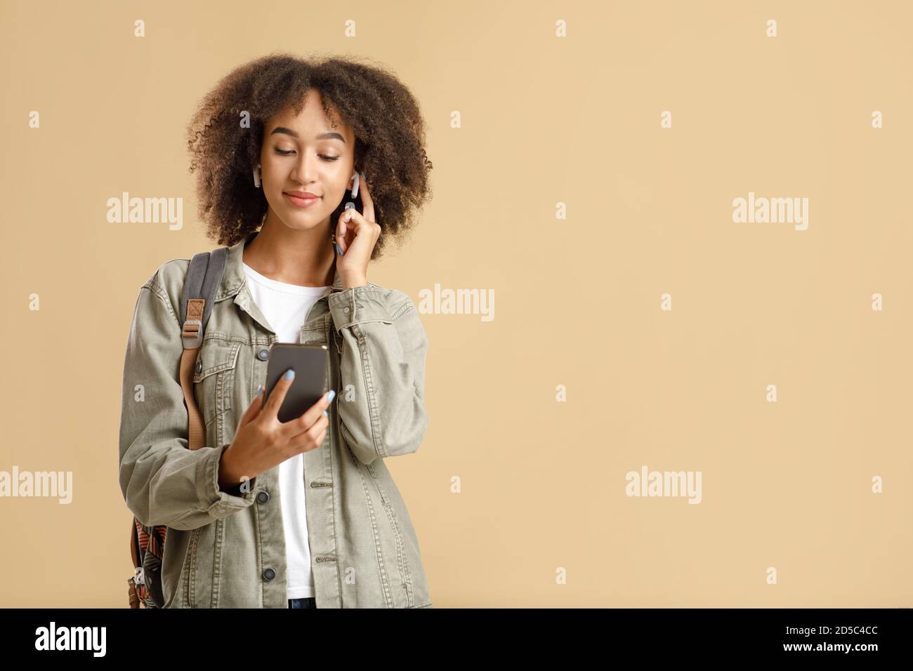 Moderne Geräte für Millennials. Ruhige afroamerikanische junge Frau setzt kabellose Kopfhörer auf Stockfoto