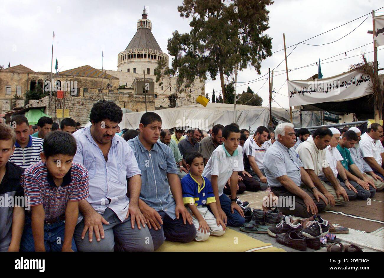 Hunderte von israelischen Arabern dringen von der behelfsmäßigen Shaheb el-DIN Moschee (R) auf die Straße, während sie während der Freitagsgebete am 8. Oktober in einer Demonstration knien, die aufgerufen ist, gegen die Opposition des Vatikans gegen eine Moschee, die an diesem Ort gebaut wird, zu protestieren. Der wichtigste christliche Wallfahrtsort in Nazareth, die Basilika der Verkündigung, ist dahinter zu sehen. [Ein hochrangiger katholischer Beamter im Heiligen Land, Wadee Abu Nasser, sagte, dass Spannungen über den umstrittenen kleinen Platz Pläne für einen päpstlichen Besuch im März 2000 in Gefahr bringen könnten.] ??» Stockfoto