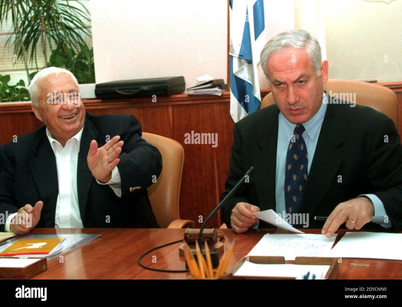 Premierminister Benjamin Netanjahu (R) schaut aus seinen Papieren, während Außenminister Ariel 'Arik' Sharon einem Minister am Tisch zumutet, als am 5. November die Kabinettssitzung zur Ratifizierung des Wye-Friedensabkommens beginnt. Nach tagelangen Verzögerungen setzte sich das Kabinett schließlich zu einer Marathonsitzung zusammen, bei der Israels Interims-Friedensabkommen mit den Palästinensern ratifiziert werden sollte. Stockfoto