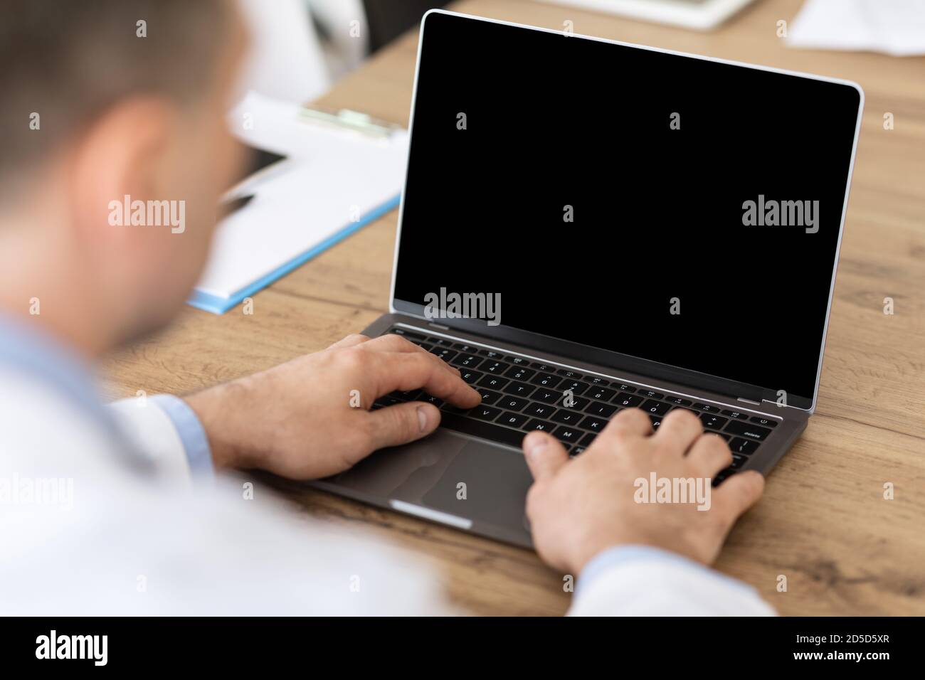 Mann arbeitet auf Laptop mit leerem schwarzen Bildschirm für mockup Stockfoto