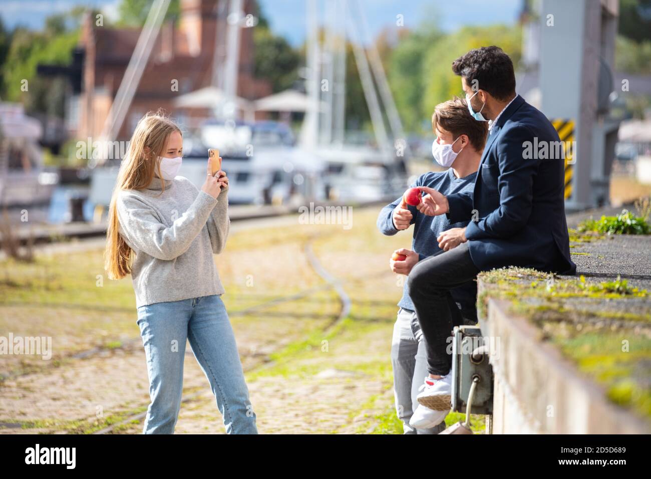 Zwei Männer und eine Frau in Corona-Zeit, mit Alltagsmasken, in der Stadt. Freizeit mit Maske im Freien. Stockfoto