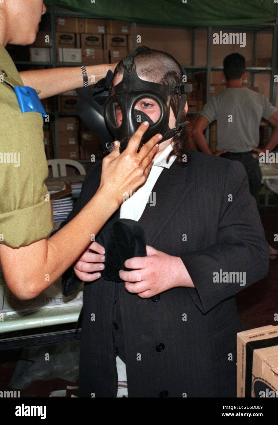 Ein israelischer Soldat trägt eine Gasmaske auf einen ultra-orthodoxen  jüdischen Jungen, während er seine "Yalmuka" am 13. November hält.[Israelis  strömten heute in dieses Gasmasken-Verteilungszentrum, um alte Masken gegen  neue auszutauschen, während ...
