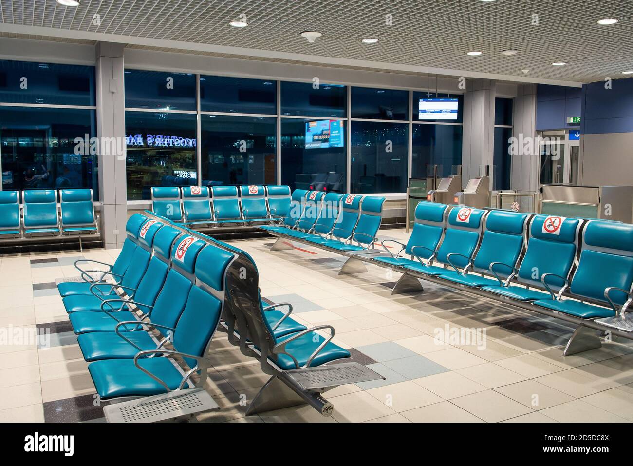 Der Warteraum an einem leeren Flughafen. Warteraum mit Metallstühlen mit Schild für die Beobachtung der Distanz. Halten Sie Ihre Distanz. Verhinderung der Ausbreitung von CO Stockfoto