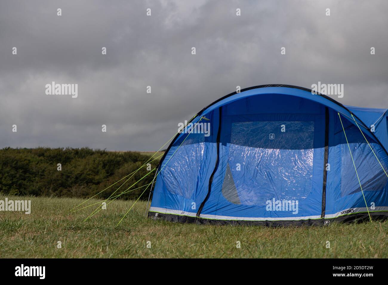 Ein einziges modernes blaues Zelt mit verschiedenen Kulturen und Winkeln In einem Feld mit Kopieplatz, um im Camping zu verwenden Geschichten Stockfoto