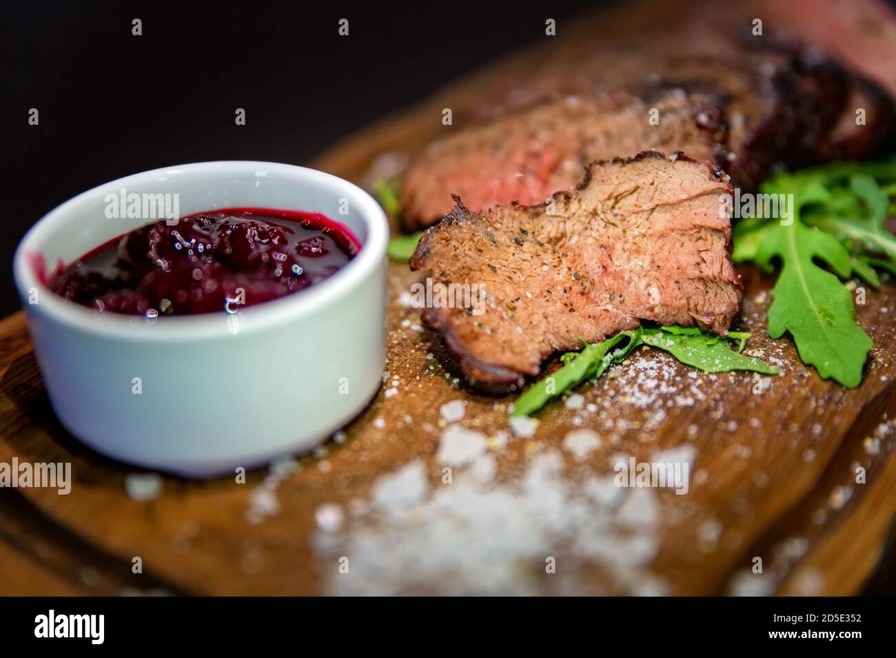 Kirschsauce mit mittelseltenem gebackenem Kalb, grobem Salz, Gewürzen und Rucola-Blättern Stockfoto