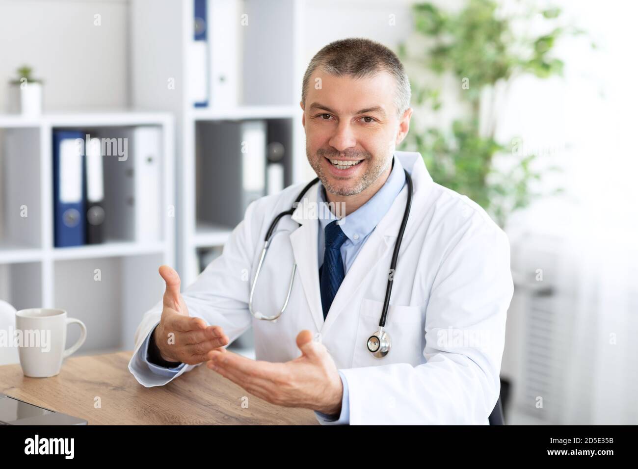 Porträt eines reifen Arztes, der seinen Klienten, den pov des Patienten, konsultiert Stockfoto