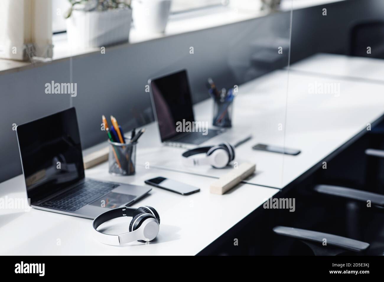 Modernes Büro zur sozialen Distanzierung von Arbeitern nach der Sperre. Arbeitsplätze mit Laptops, Smartphones, Kopfhörern Stockfoto