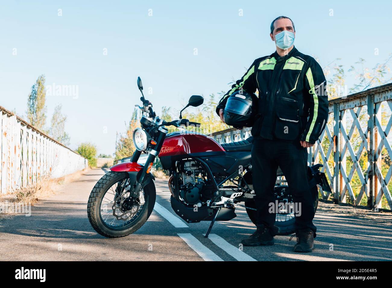 Biker mit einer medizinischen Maske und einem Motorrad dahinter Stockfoto