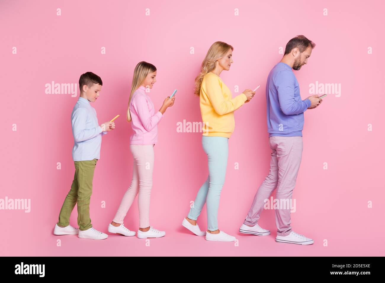 Ganzkörper-Profil Seitenfoto von Papa Mama kleine Kinder Gehen Sie die Eingabe von sms auf dem Smartphone isoliert über Pastellfarben Hintergrund Stockfoto