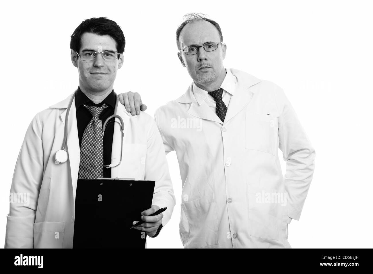 Reifer mann Arzt mit der Hand auf die Schulter des jungen Mannes Arzt holding Zwischenablage Stockfoto