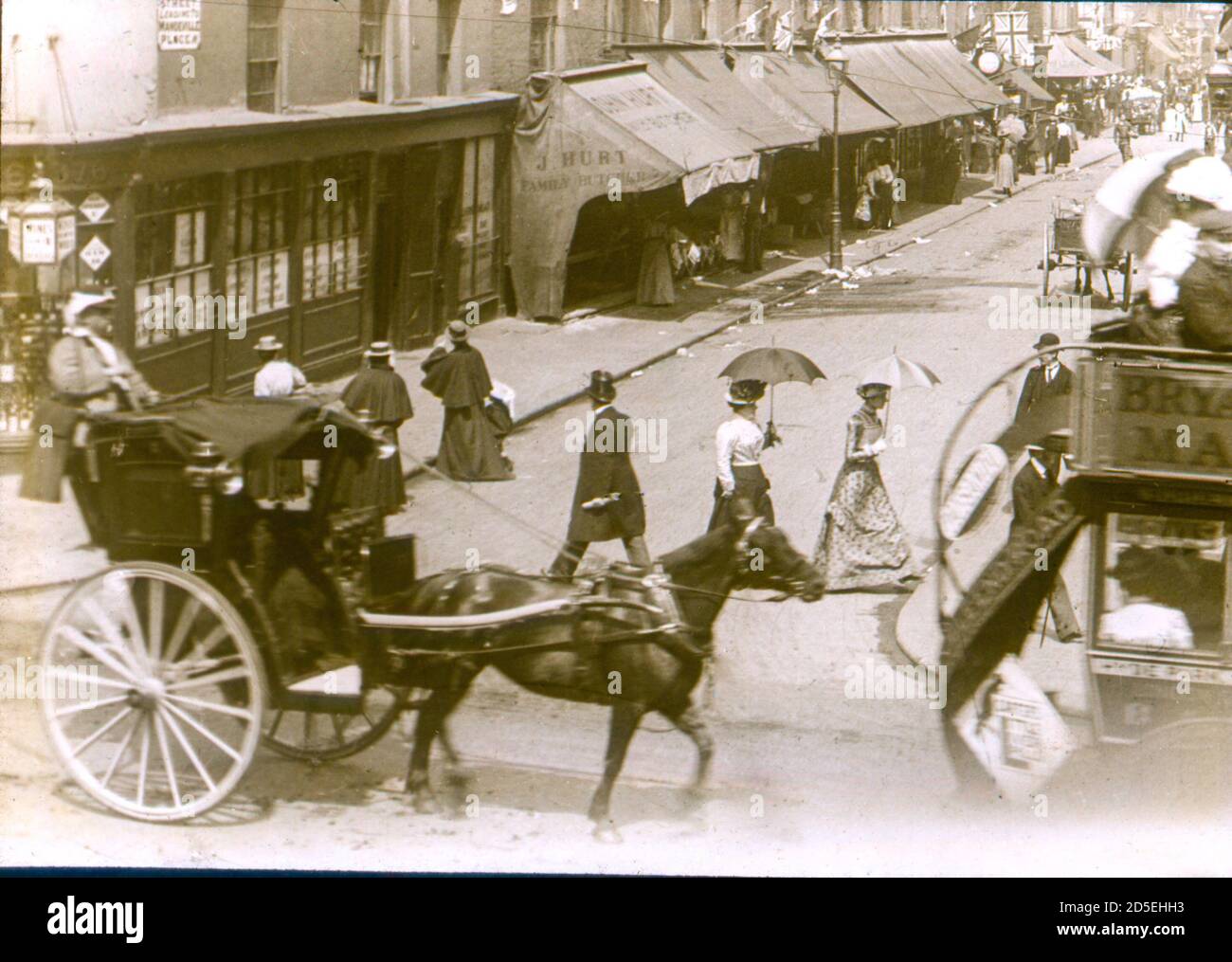 Viktorianische Menschen reisen herum und machen ihre Einkäufe im London des 19. Jahrhunderts, an der Kreuzung von St James Street und Oxford Street. Zu sehen sind die Flaggen und die Fahnen, die den 80. Geburtstag von Königin Victoria feiern. Stockfoto