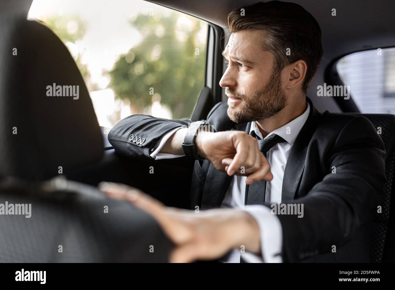 Hübscher bärtiger Mann im Anzug, der im Auto sitzt Stockfoto