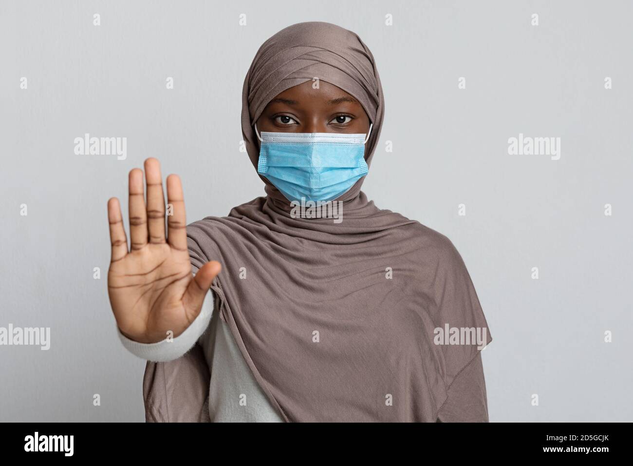 Stoppen Sie Die Coronavirus-Pandemie. Schwarze muslimische Frau trägt medizinische Maske zeigt Stop-Geste Stockfoto