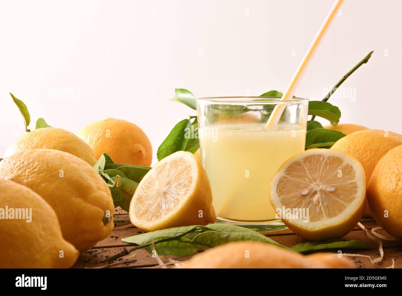 Frisch gepresster Saft auf einem Holztisch voller Zitronen mit weißem Hintergrund. Vorderansicht. Horizontale Zusammensetzung. Stockfoto