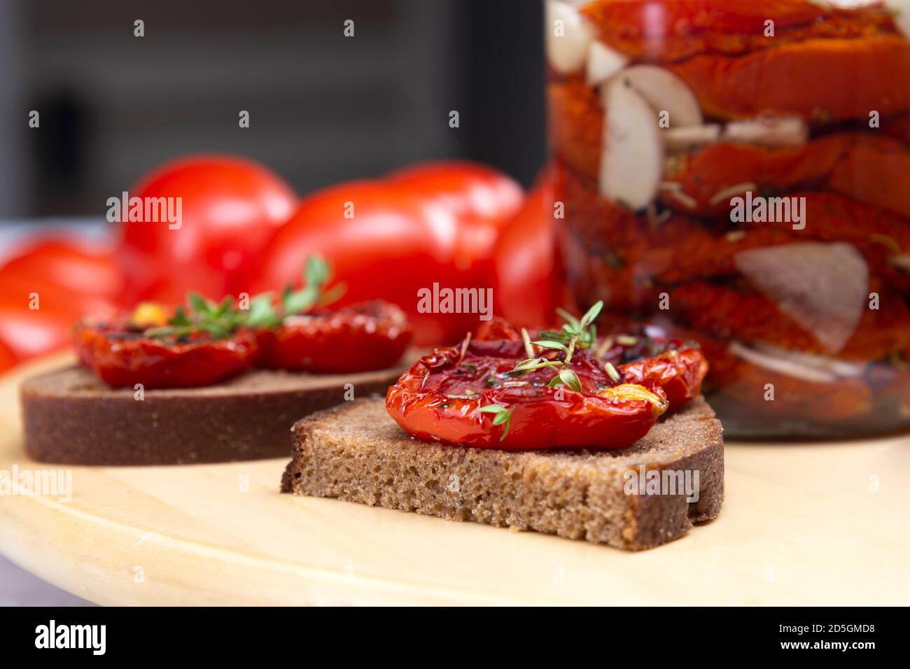 Hausgemachte sonnengetrocknete Tomaten mit Olivenöl in einem Glas. Sandwich mit schwarzem Brot und sonnengetrockneten Tomaten Stockfoto