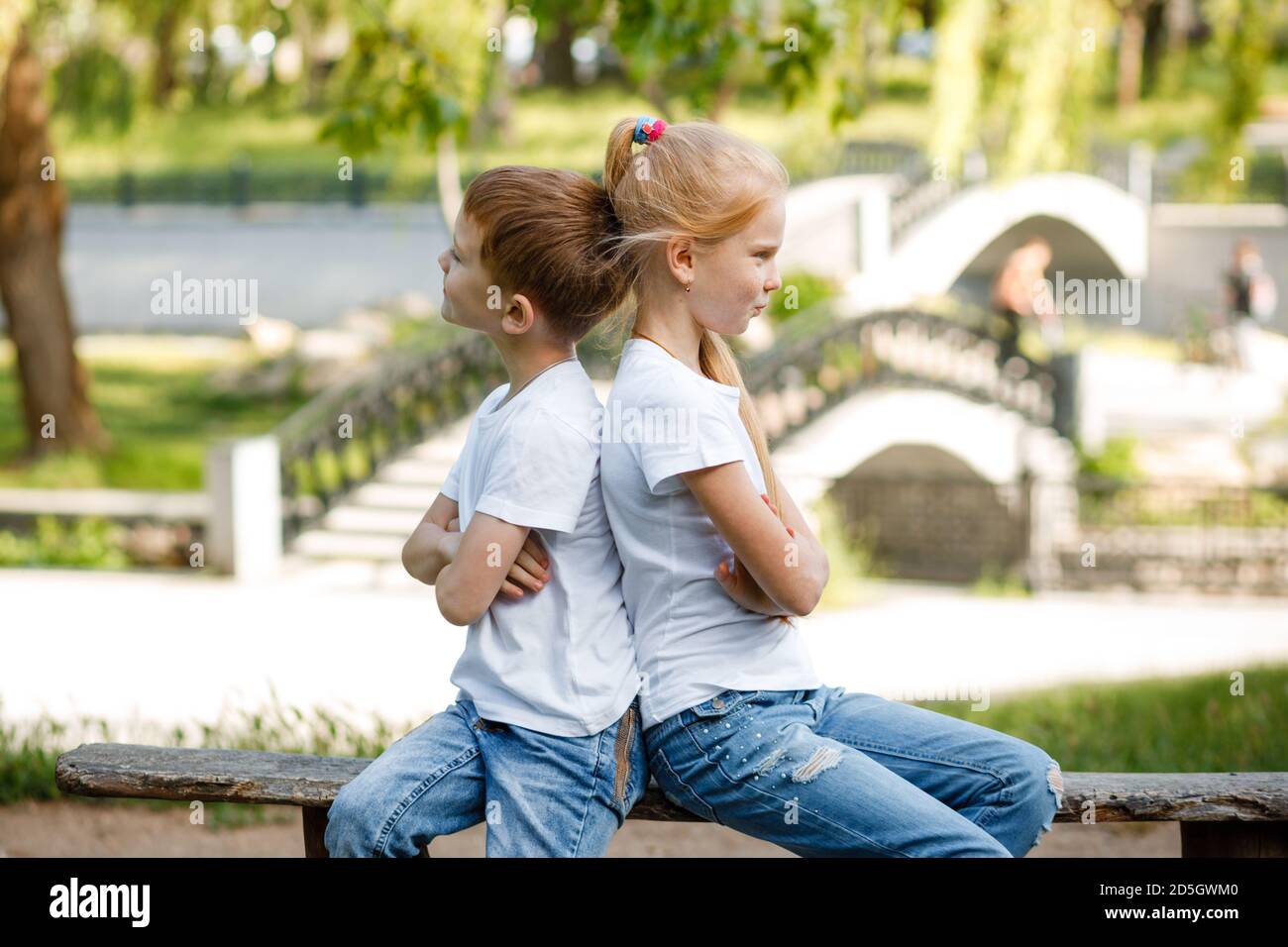 Die Kinder vergehen sich gegenseitig im Park auf der Bank. Stockfoto