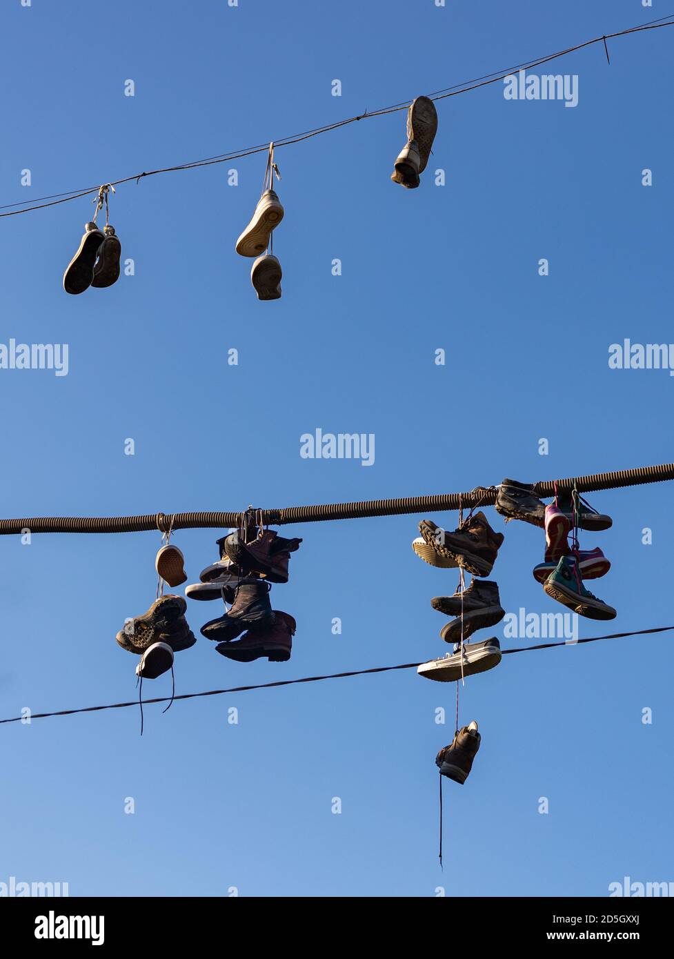 Ein Bild von einem Haufen von Schuhen, die an Stromkabeln im Metelkova Art Center hängen. Stockfoto