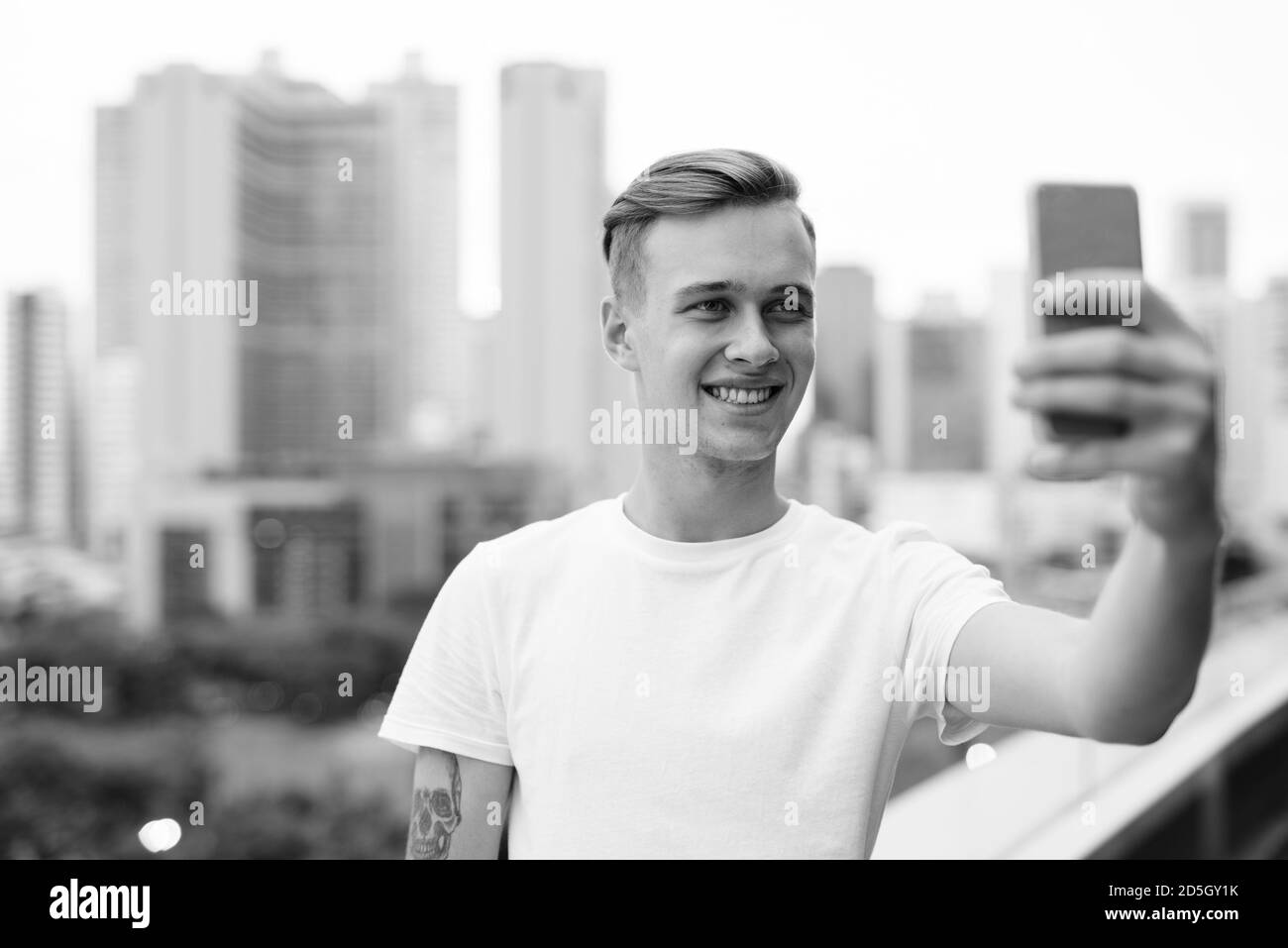 Junger stattlicher Mann mit blonden Haaren gegen den Blick auf die Stadt Stockfoto