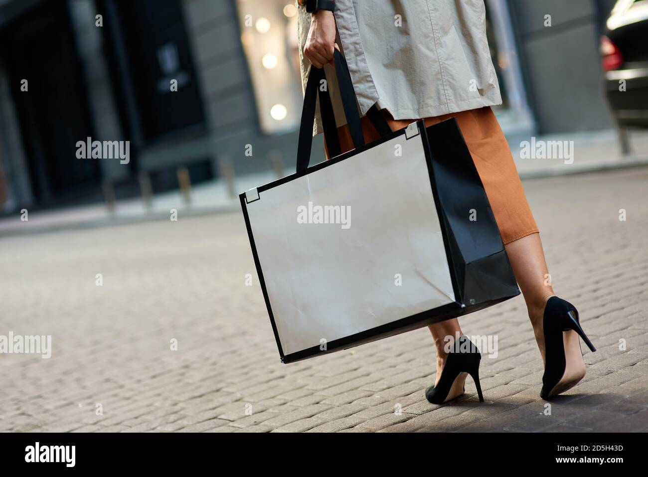 Kurze Aufnahme einer Frau in Schuhen mit hohem Absatz, die eine große Einkaufstasche tragen und durch die Straßen der Stadt laufen. Mode, Menschen Lifestyle-Konzept Stockfoto