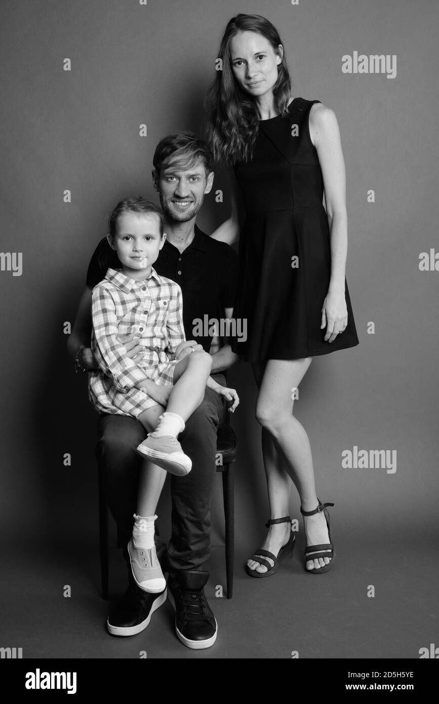 Junge, glückliche Familie kleben zusammen gegen grauer Hintergrund Stockfoto