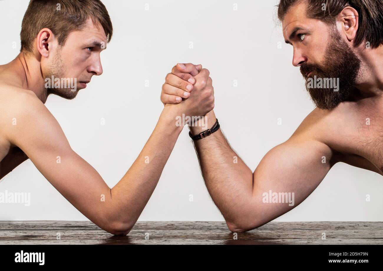 Zwei Männerhände umklammten Arm Wrestling, stark und schwach, ungleiche Übereinstimmung. Stark muskulös bärtigen Mann Arm Ringen ein mickrigen schwachen Mann. Arme ringen dünn Stockfoto