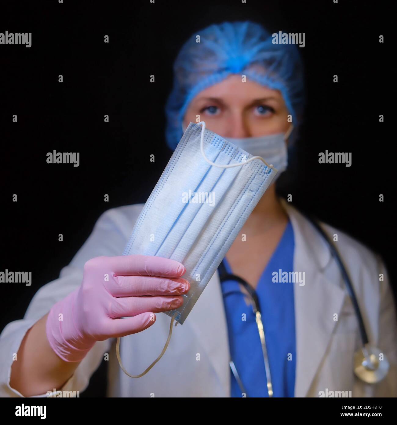Arzt mit einer medizinischen Maske in der Hand, Nahaufnahme. Krankenschwester gibt Gesichtsmasken auf schwarzem Hintergrund. Coronavirus pandemische Schutzkleidung Konzept Stockfoto