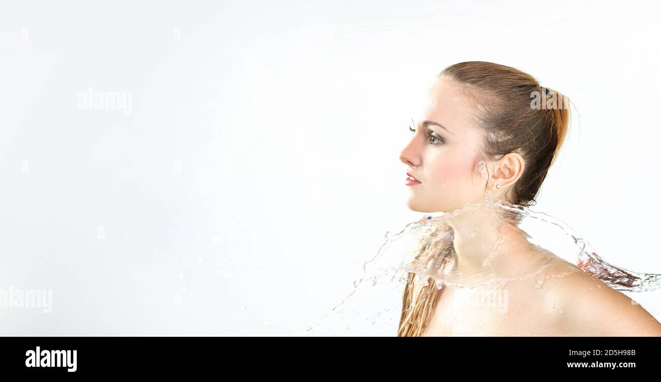 Hübsche Frau mit Wasserspritzer. Schöne Model Frau mit einem Spritzer Wasser. Schöne lächelnde Mädchen unter Wasser mit frischer Haut auf blauem Hintergrund. Sk Stockfoto