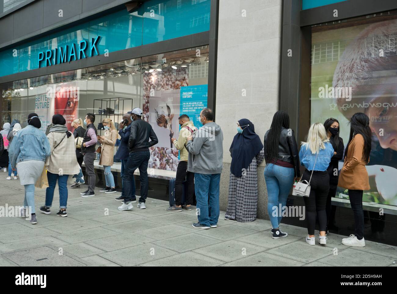 Einkäufer in der Oxford Street, in der Schlange, um Primark-Laden mit Schildern, die darauf hinweisen, um sichere soziale Distanz wegen Coronavirus / Covid-19 Pandemie in London, England, Großbritannien zu halten Stockfoto