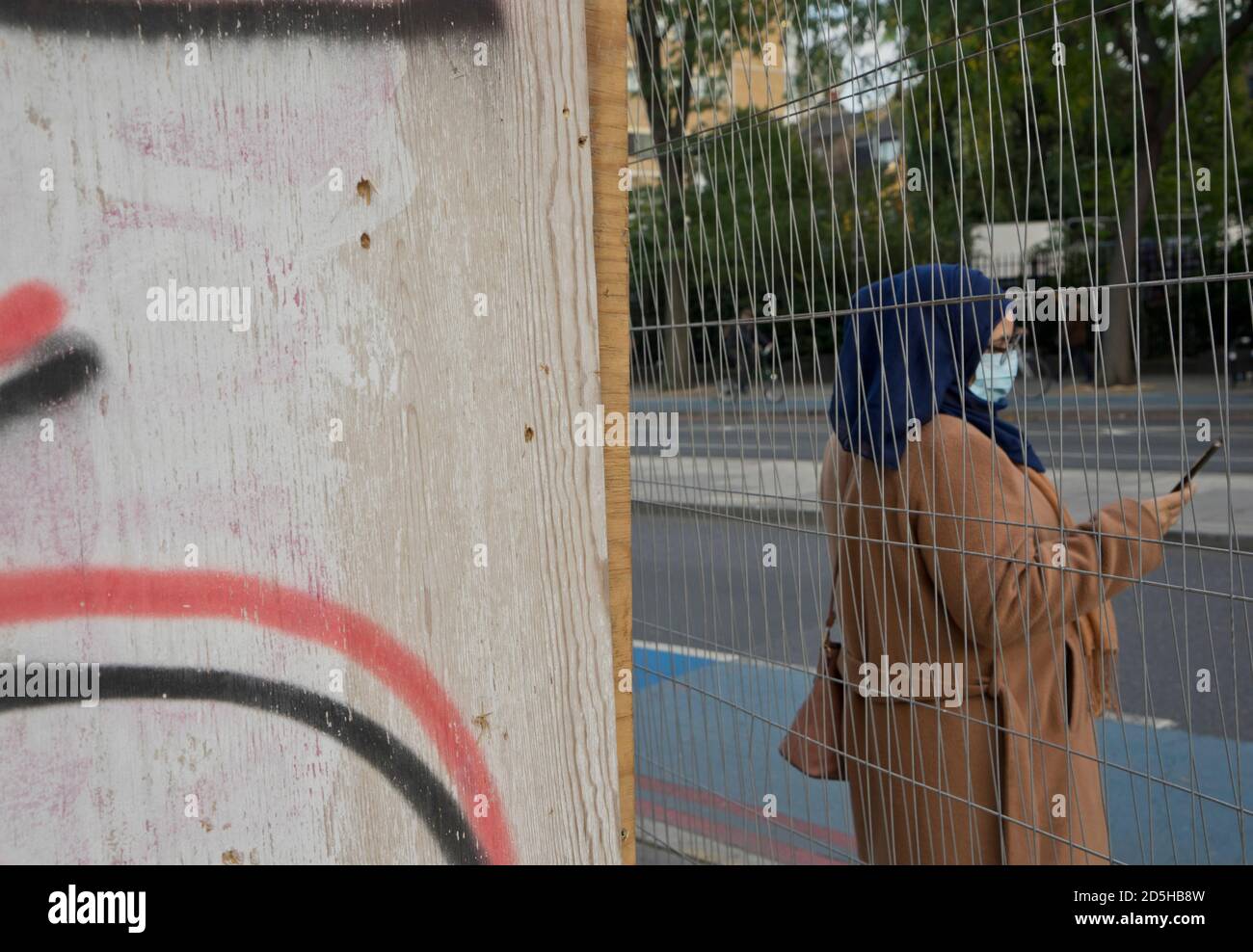 Lokale muslimische Frau mit Gesichtsmaske in Whitechapel, mit Schildern beraten, um sichere soziale Distanz wegen Coronavirus / Covid-19 Pandemie in London, England, Großbritannien zu halten Stockfoto