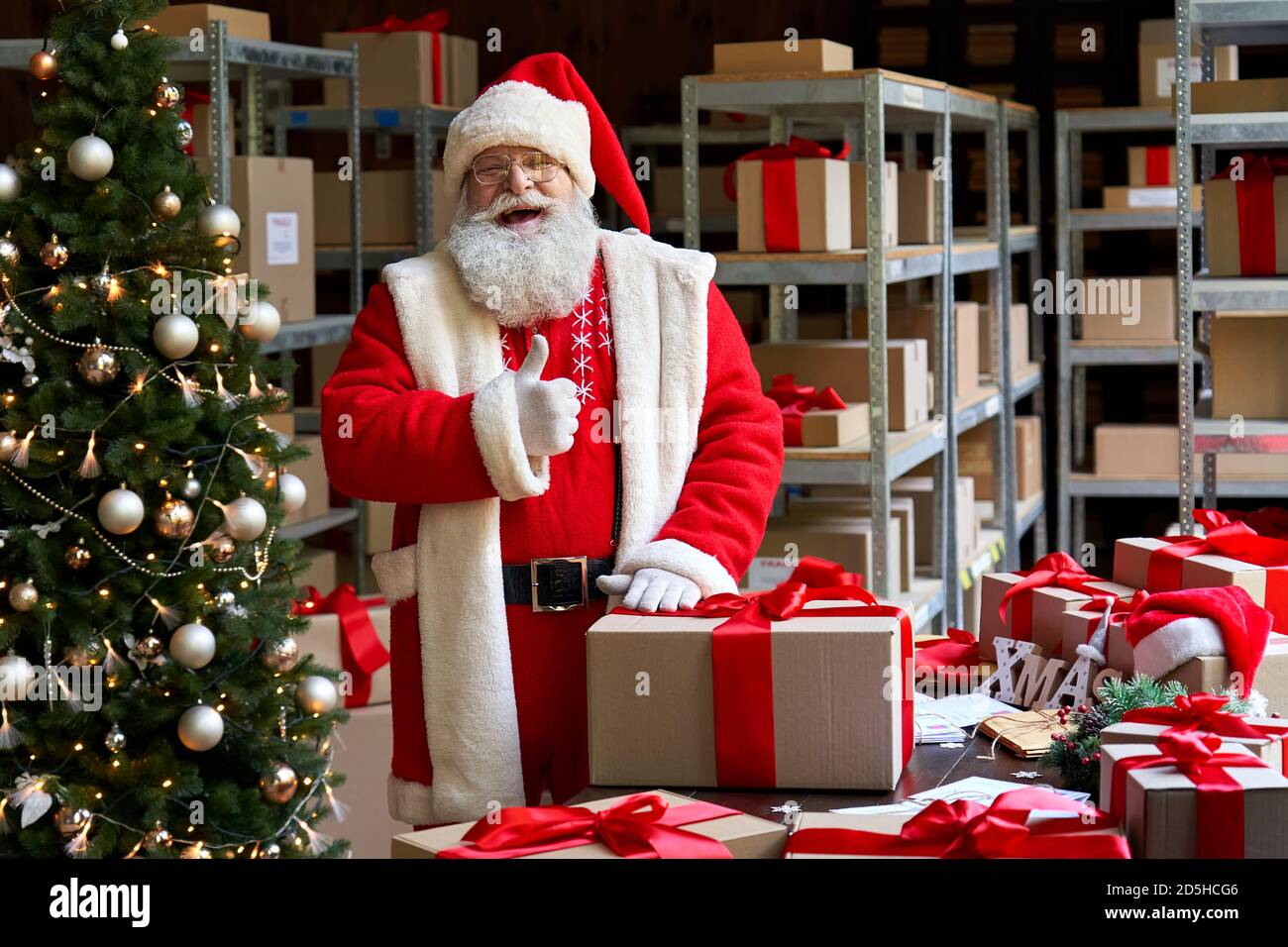 Happy Santa Claus trägt Kostüm zeigt Daumen nach oben stehen in der Werkstatt. Stockfoto