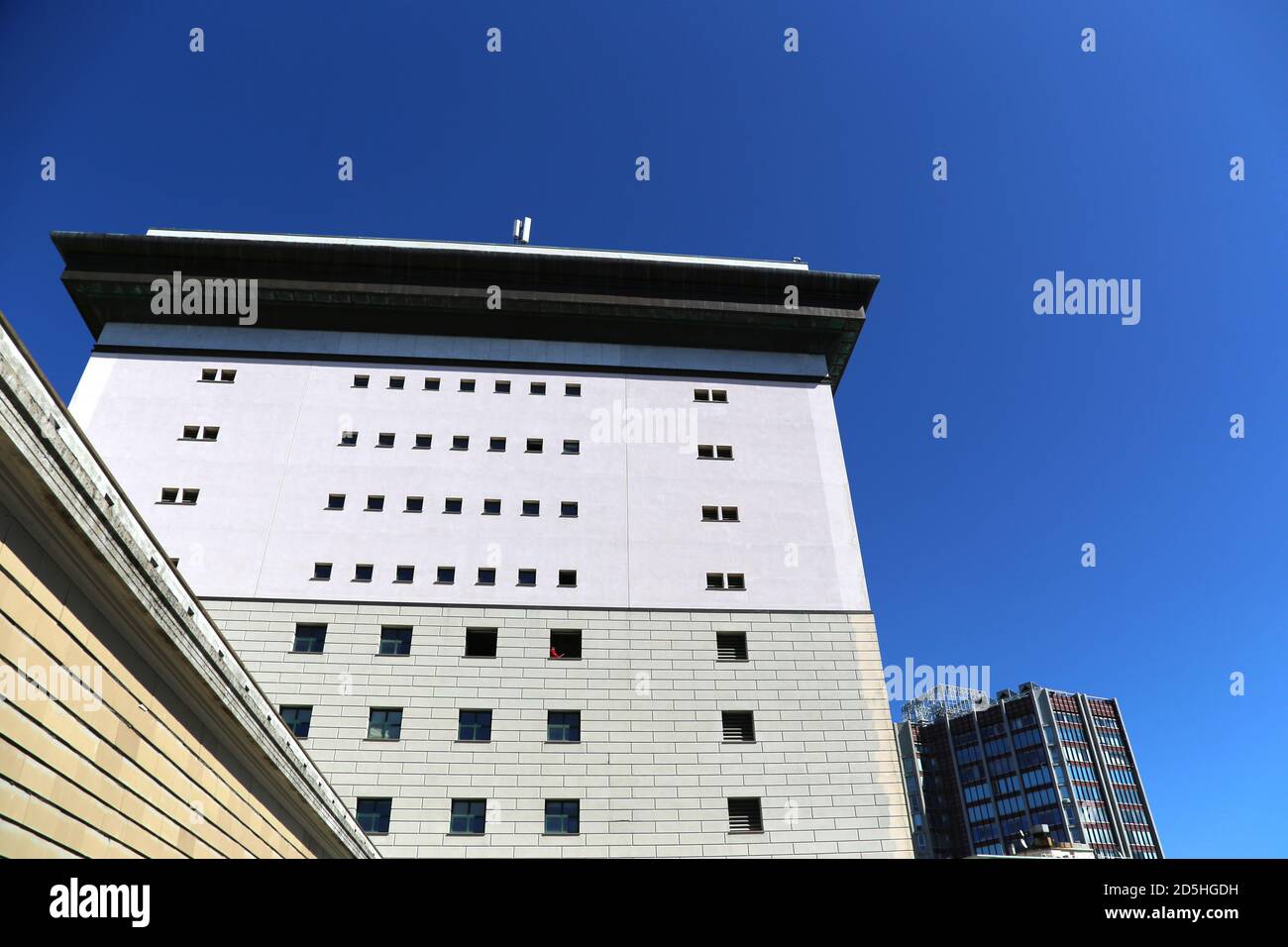 Blick auf das hohe Gebäude in Parallelepiped-Form des Opernhauses von Genua mit seinen charateristischen quadratischen Fenstern vor einem markanten blauen Himmel. Im Stockfoto