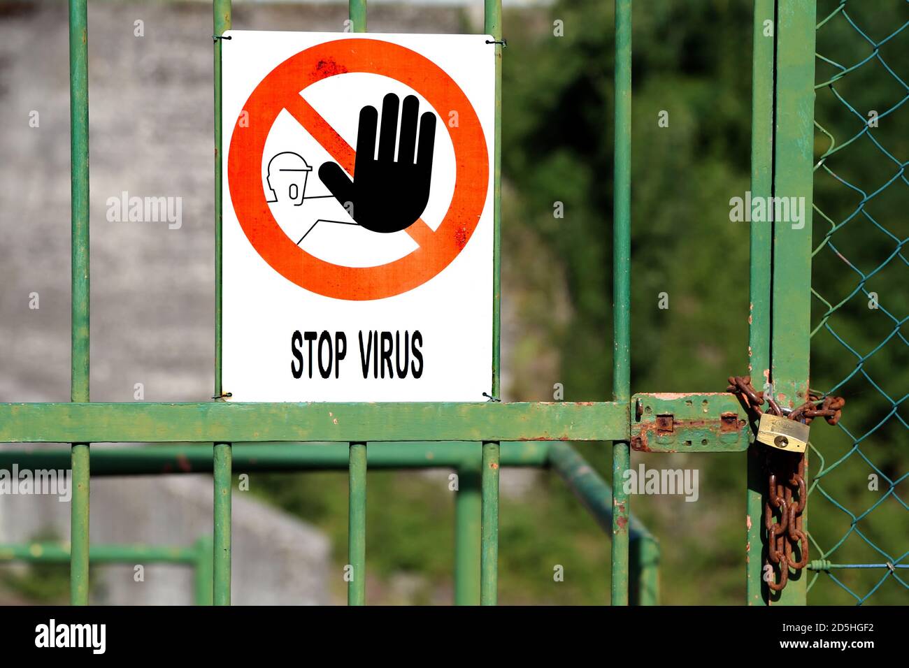 Tor geschlossen mit Vorhängeschloss und rotes Schild mit großen schwarzen Hand zeigt an, zu stoppen und große Nachricht STOPPEN VIRUS. Stockfoto