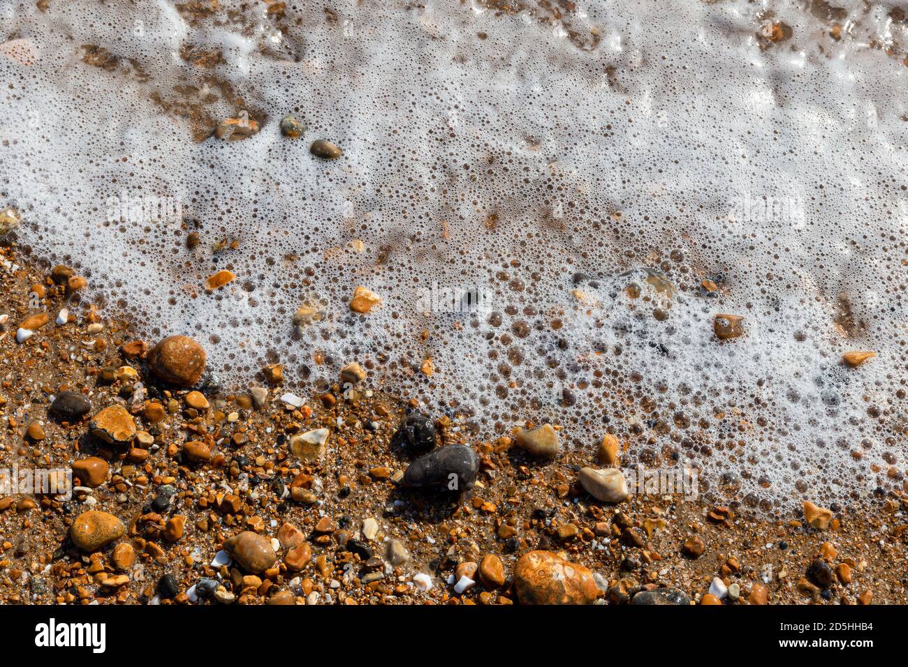 Wellen lappen die Kiesel am Brighton Beach, England, Großbritannien Stockfoto