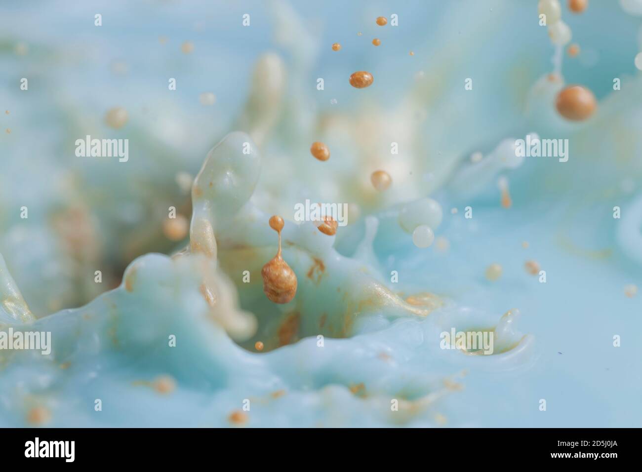 Goldfarbe spritzt in schöne türkisfarbene Farbe schaffen viele Farbblasen und Tröpfchen und andere Effekte. Stockfoto