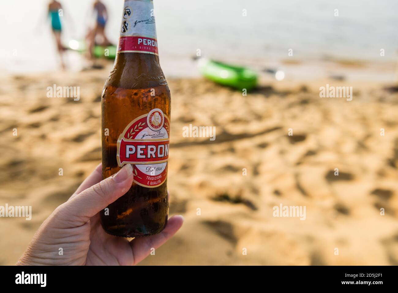 peroni Bier in der Hand am Strand Stockfoto
