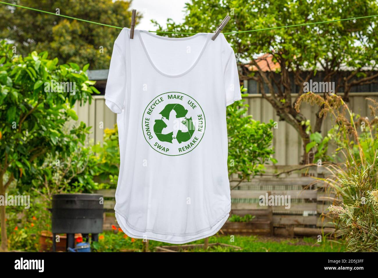 T-Shirt auf Wäscheleine mit kreisförmigen Wirtschaft Textilien Symbol, machen, verwenden, wiederverwenden, tauschen, spenden, recyceln mit Öko-Kleidung recyceln Symbol nachhaltige Mode Stockfoto