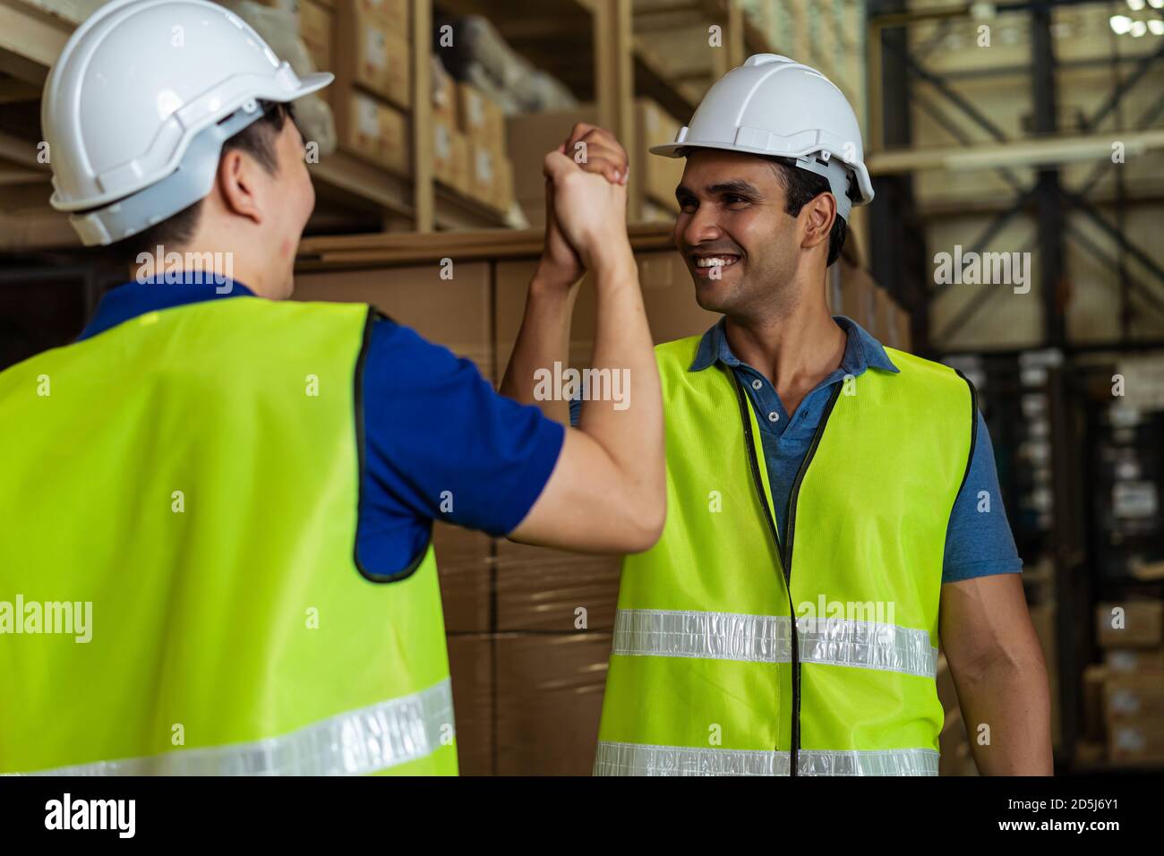 Indische männliche Fabrik Lagerarbeiter arbeiten in der Logistikbranche indoor. Freunde begrüßen und tun Handschlag mit der Hand greifen im Depot Stockfoto