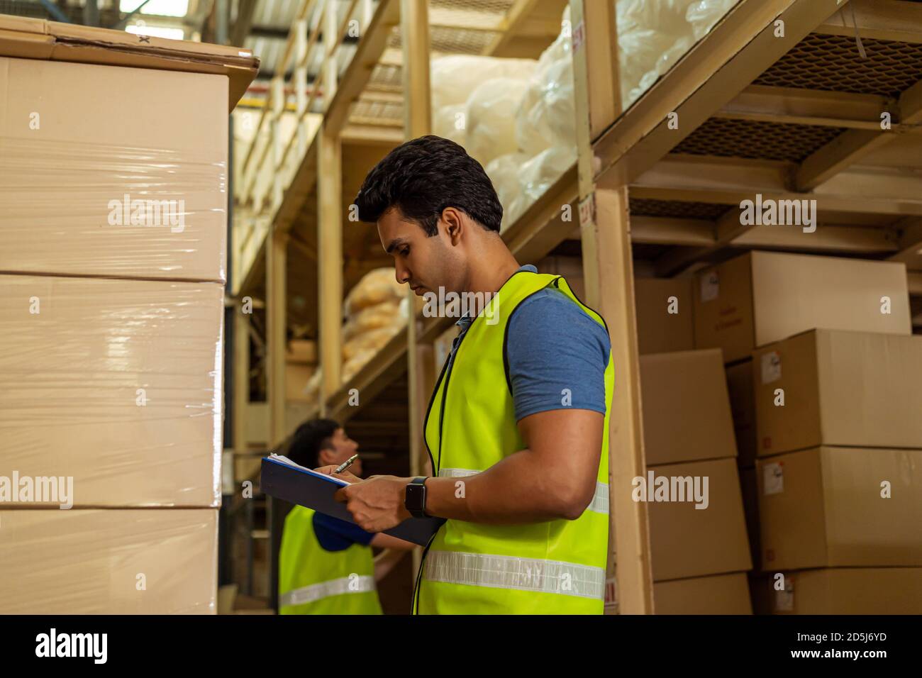 Gruppe von jungen industriellen Fabrik Lagerarbeiter arbeiten in der Logistikindustrie indoor. Asiatische und indische ethnische Männer Mann hält eine Zwischenablage Überprüfung Stockfoto