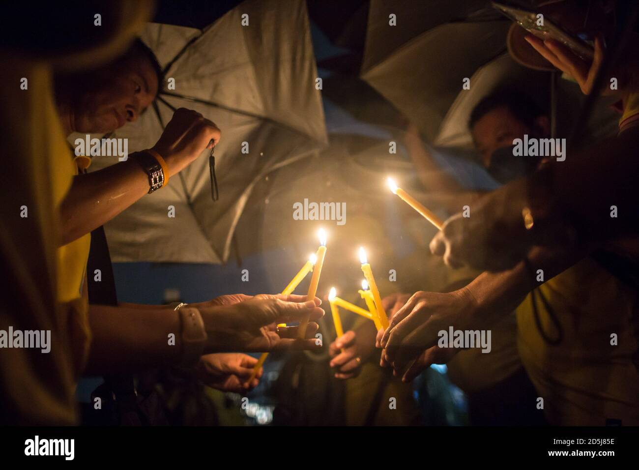 Bangkok, Thailand. Oktober 2020. Royalist Anhänger halten Regenschirme, um sich vor dem Regen zu schützen halten Kerzen während der vierten Jahrestag Zeremonie anlässlich des Todes des verstorbenen thailändischen Königs Bhumibol Adulyadej (Rama 9). Kredit: SOPA Images Limited/Alamy Live Nachrichten Stockfoto