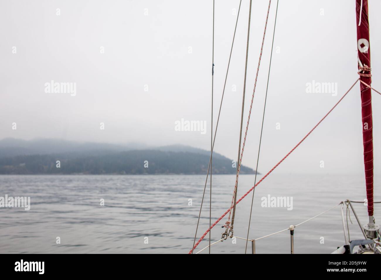 Ein Segelboot fährt an einem ruhigen Tag durch den Nebel an der Küste von British-Columbia vorbei, entlang des pazifischen Nordwestens Stockfoto