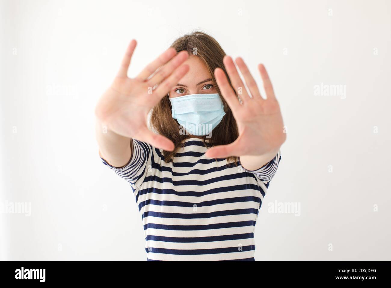 Frau in Maske macht Stop-Geste Stockfoto