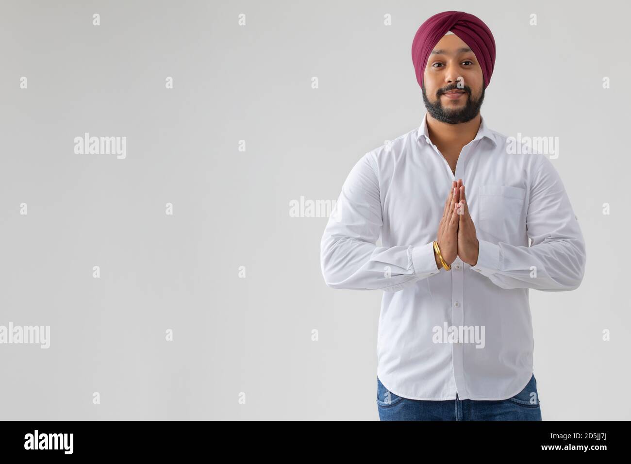 EIN SIKH-MANN BEGRÜSST MIT GEFALTETEN HÄNDEN Stockfoto