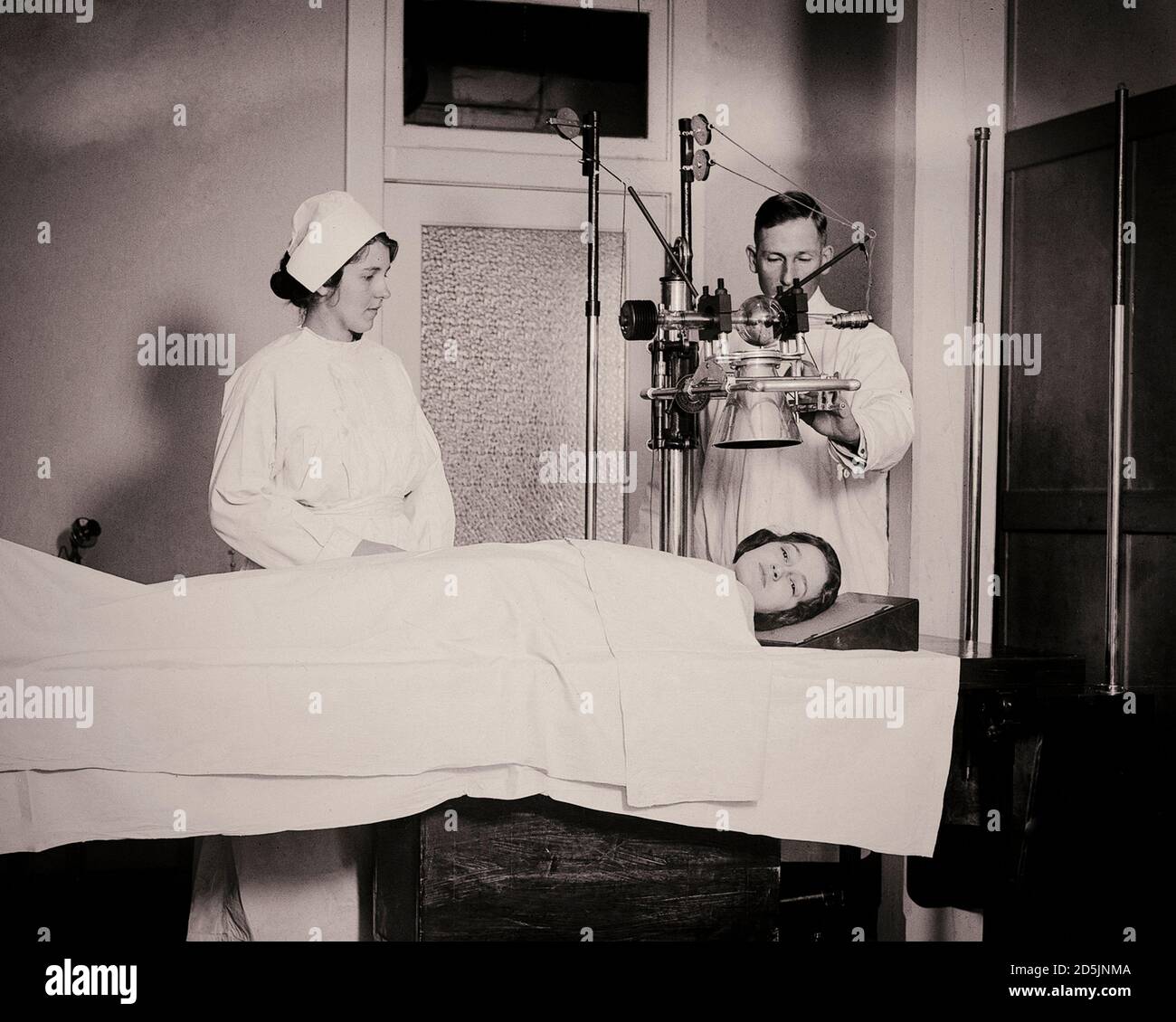 Archival photo of public hospital staff take an x-ray of a patient's head, USA, 1920. Stockfoto